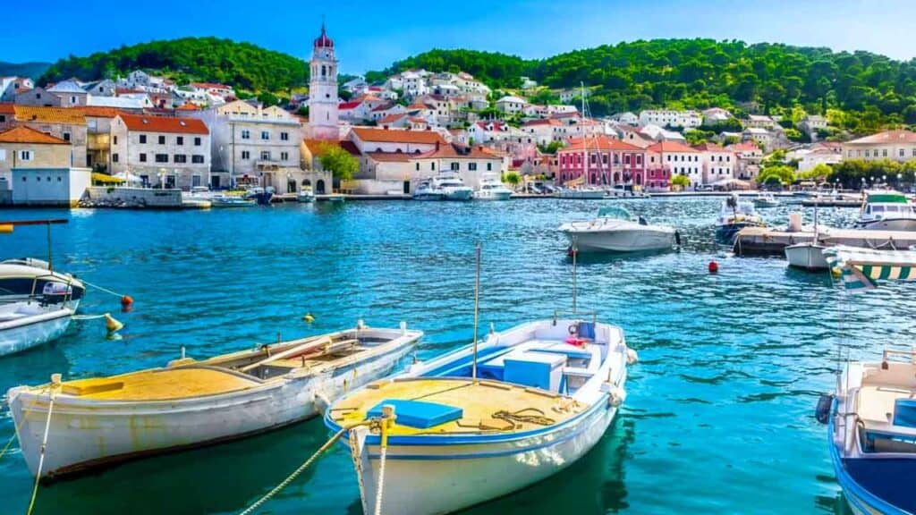 Harbour with boats and colourful seaside town in the background.