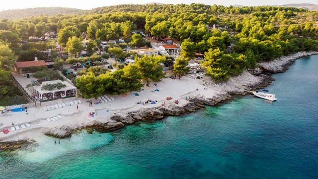 Scenic coastal view with sandy beach, clear waters, and lush greenery.