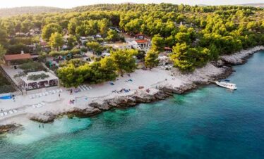 Scenic coastal view with sandy beach, clear waters, and lush greenery.