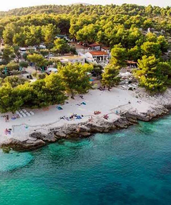 Scenic coastal view with sandy beach, clear waters, and lush greenery.