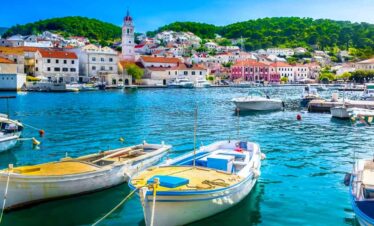 Harbour with boats and colourful seaside town in the background.