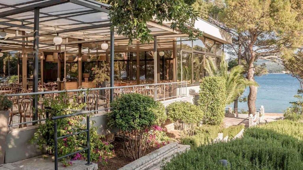 Outdoor lakeside restaurant with lush greenery and scenic water views.