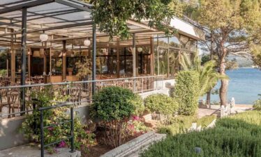 Outdoor lakeside restaurant with lush greenery and scenic water views.