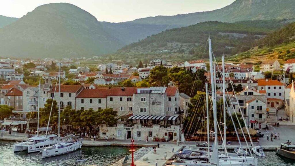 Harbour town with boats, colourful buildings, and mountain backdrop.