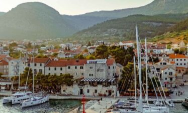 Harbour town with boats, colourful buildings, and mountain backdrop.