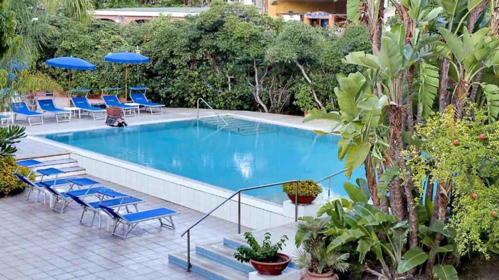 Poolside relaxation area with sun loungers and umbrellas in a lush tropical setting.