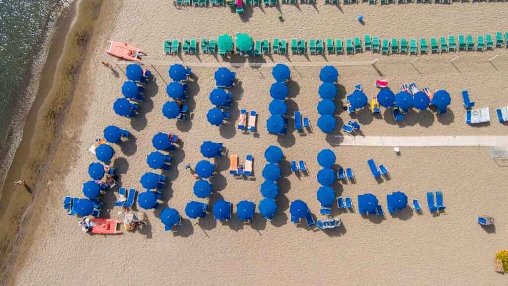 Beach umbrellas and loungers on sandy beach with waterway, ideal for relaxing holidays.
