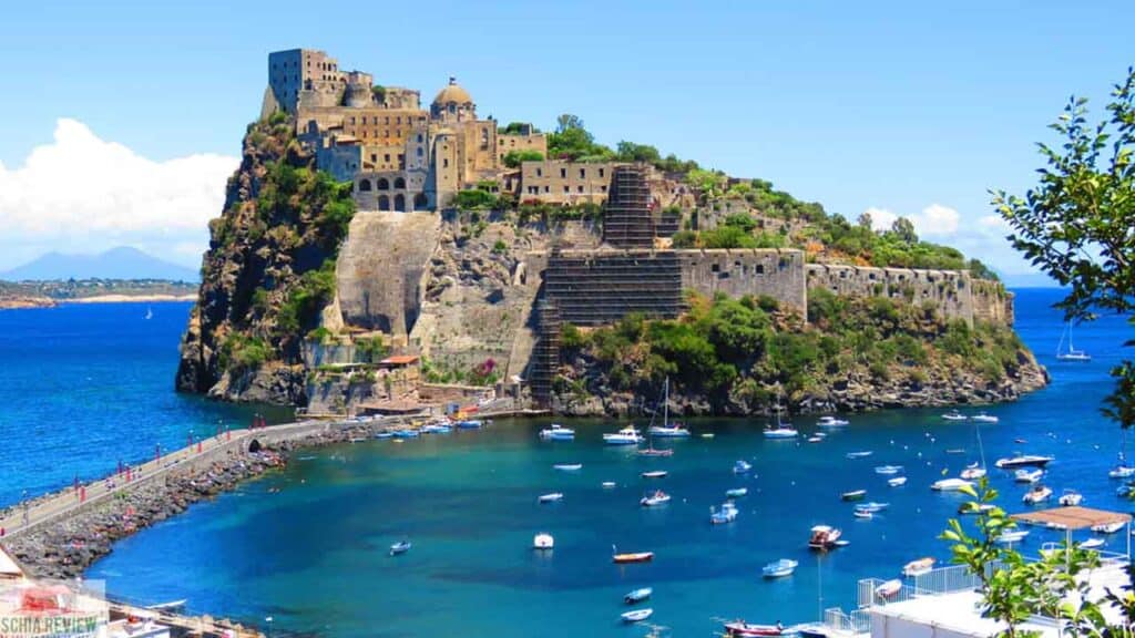 Amalfi Coast fortress overlooking the sea with boats and lush greenery in the foreground.