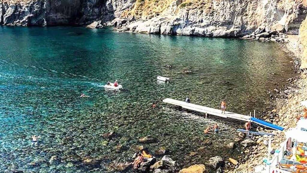 Scenic lake surrounded by rocky cliffs with boats and people enjoying the water.