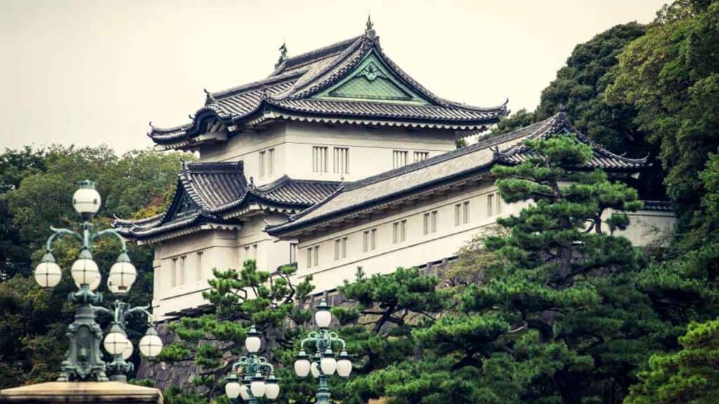 Traditional Japanese castle with ornate roof design and lush greenery.
