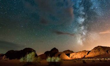 Stunning night sky with stars and Milky Way over desert landscape.