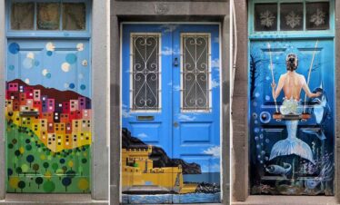 Vibrant mural on city door featuring colourful buildings and ocean-themed art.