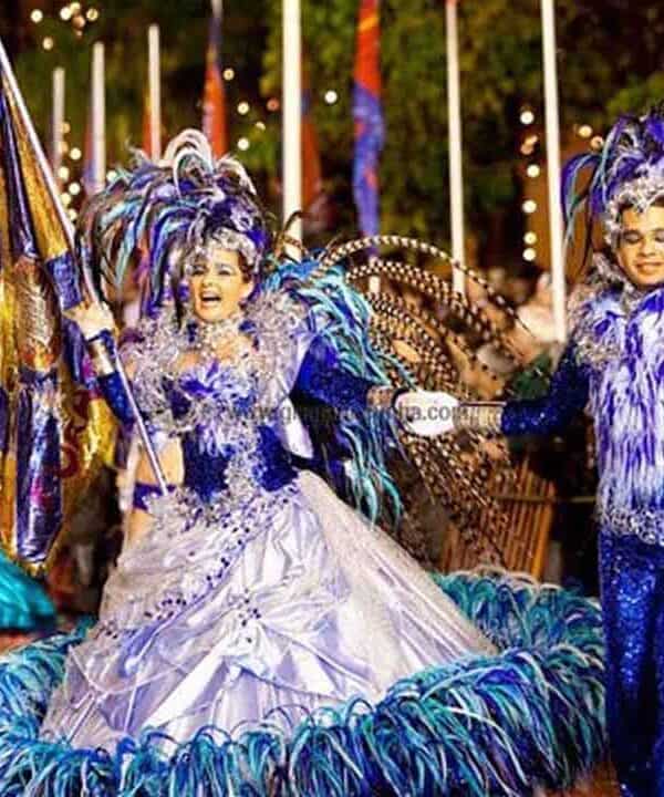 An energetic carnival parade featuring performers in colourful, elaborate costumes with feathers and.