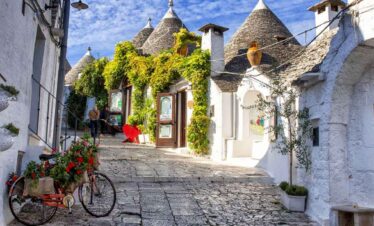 Picturesque white village with cone-shaped roofs and lush greenery, perfect for travel enthusiasts.