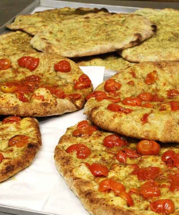 Style flatbreads topped with cherry tomatoes and herbs, freshly baked and crispy.