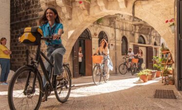 Cyclist enjoying a ride under an ancient stone archway in a charming historic city.