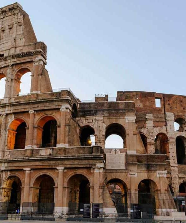 Ancient Roman Colosseum with warm sunset lighting and clear sky.