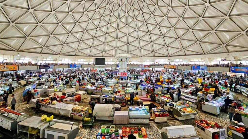 Vibrant indoor market with numerous stalls and shoppers exploring diverse products.