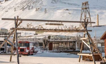 Snow-covered mountain village with rustic buildings and vintage vehicles.