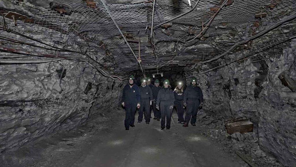 Group of people exploring an underground mine tunnel.
