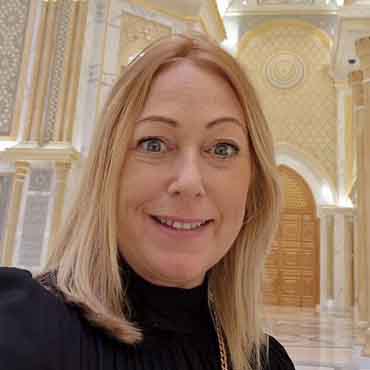 Woman smiling inside luxurious, ornate building with gold accents.