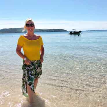 Relaxing beach holiday with a woman in a yellow top and floral skirt by the sea.