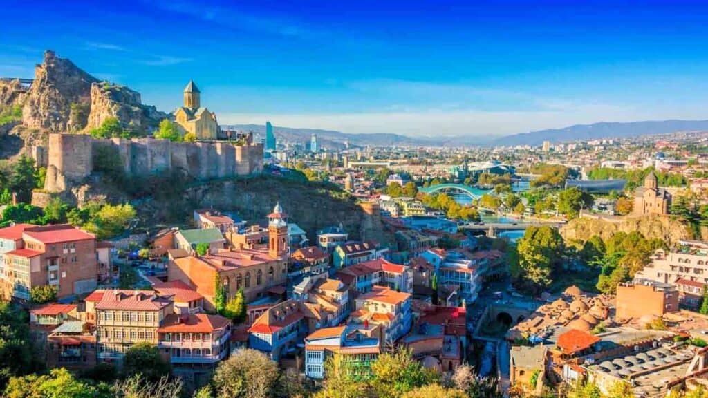 Panoramic view of Tbilisi with colourful rooftops and historic fortress.