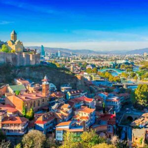 Panoramic view of Tbilisi with colourful rooftops and historic fortress.