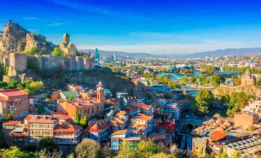 Panoramic view of Tbilisi with colourful rooftops and historic fortress.