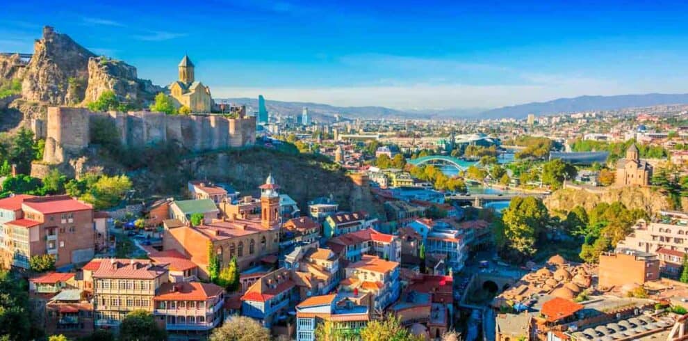 Panoramic view of Tbilisi with colourful rooftops and historic fortress.