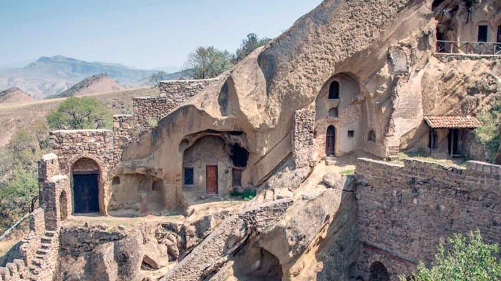 Ancient cave dwellings built into a mountain cliff, showcasing historical architecture and unique li.