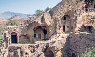 Ancient cave dwellings built into a mountain cliff, showcasing historical architecture and unique li.