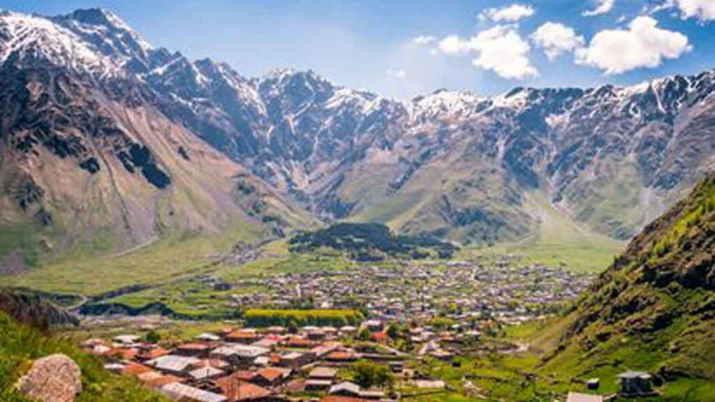 Beautiful mountain valley with a village surrounded by towering snow-capped peaks.