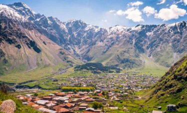 Beautiful mountain valley with a village surrounded by towering snow-capped peaks.