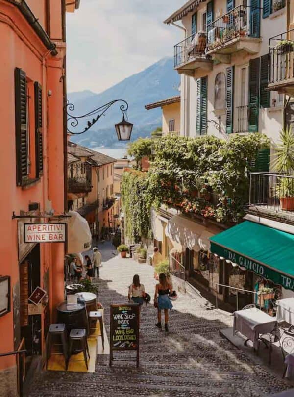 Picturesque cobbled street with colourful buildings and outdoor cafes in a scenic mountain town.