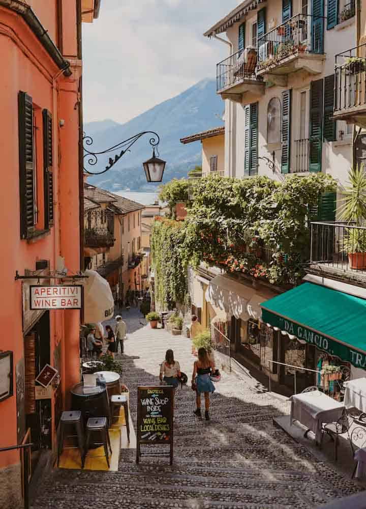 Picturesque cobbled street with colourful buildings and outdoor cafes in a scenic mountain town.
