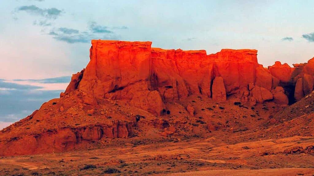 Red sandstone rock formations at sunset in a desert landscape.