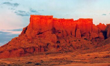Red sandstone rock formations at sunset in a desert landscape.
