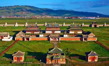 Ancient Mongolian monastery complex with traditional architecture and lush green surroundings.