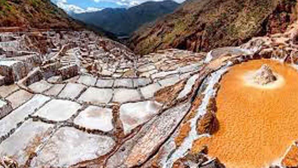 Hot springs in a mountainous landscape with mineral-rich, orange-toned waters.