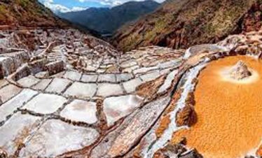 Hot springs in a mountainous landscape with mineral-rich, orange-toned waters.