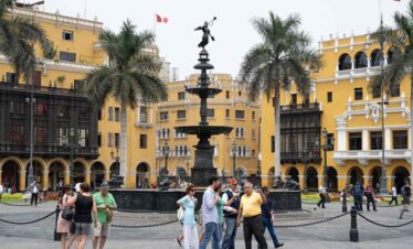 Colourful city square with tourists enjoying the lively atmosphere and central fountain.