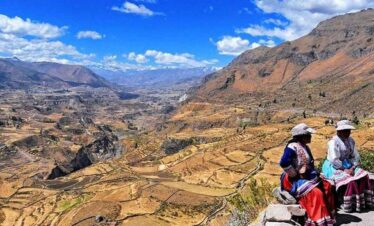 Two women in traditional clothing sitting in the Andes mountains.