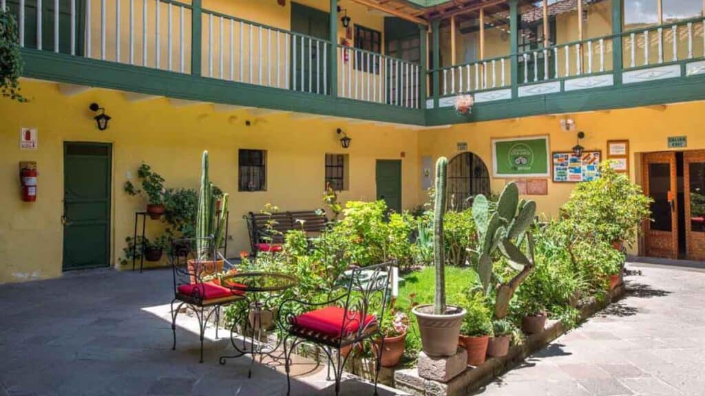 Courtyard with outdoor seating and lush plants at Travel Buddies Holidays hostel in a colourful buil.