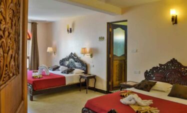 Comfortable hotel room featuring twin beds, ornate headboards, and warm lighting for a relaxing stay.