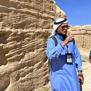 Man in traditional Middle Eastern attire exploring desert landscape.