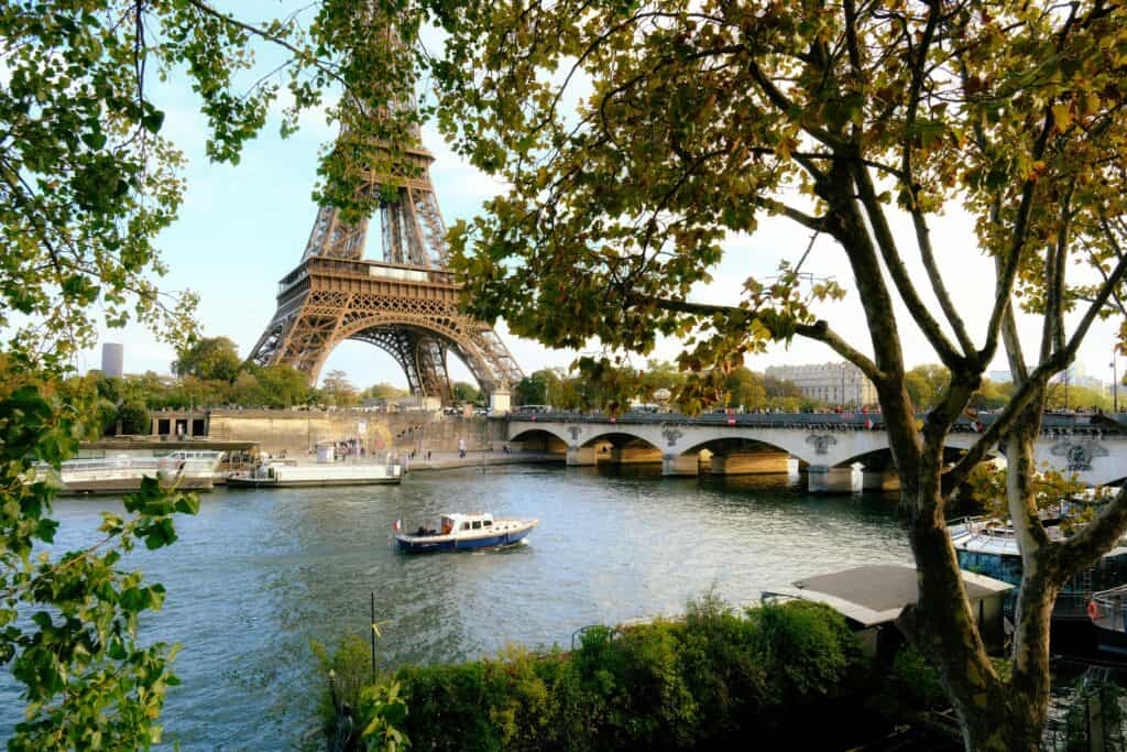 Eiffel Tower and Seine River scene with boats and trees in Paris, France.