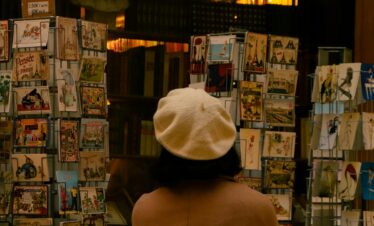 Woman browsing postcards at a travel shop for holiday ideas.