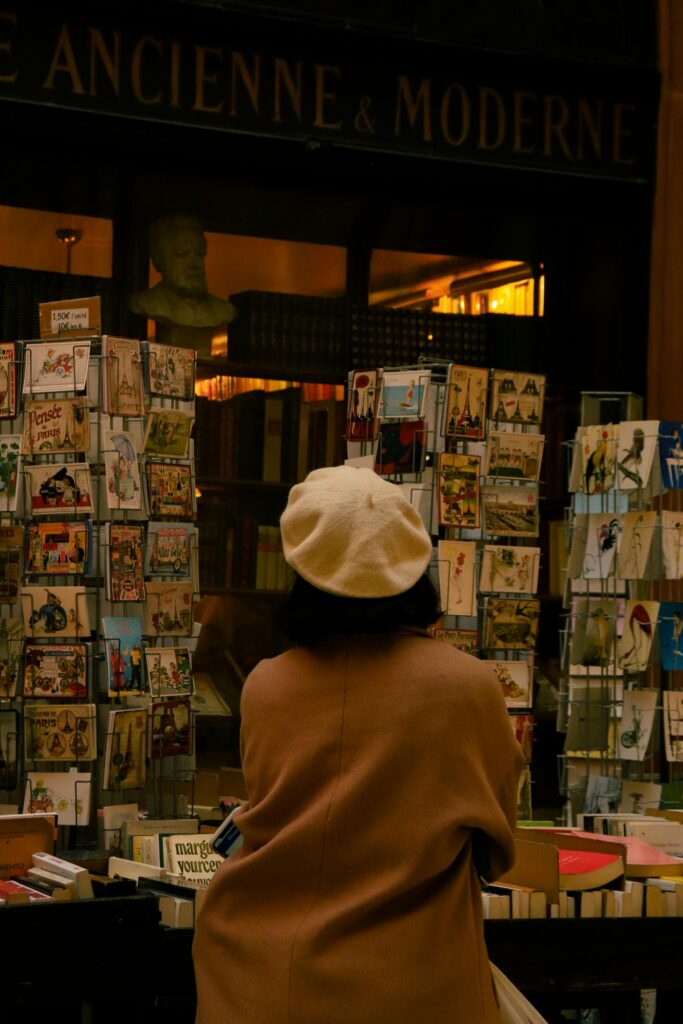 Woman browsing postcards at a travel shop for holiday ideas.
